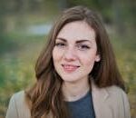 Close-up portrait of a smiling woman with freckles and long hair in a Budapest park during fall.
